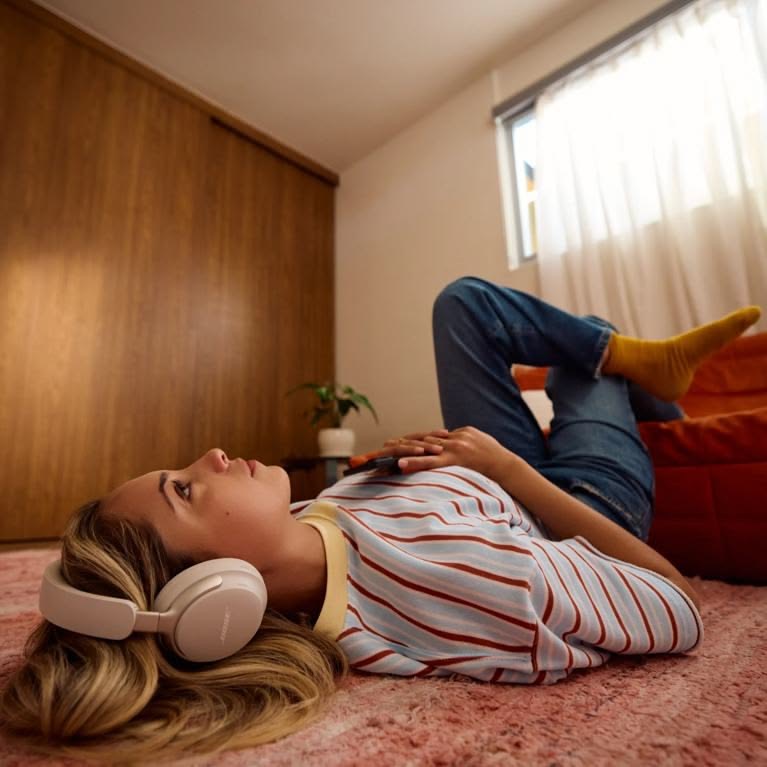 Žena leží na koberci so slúchadlami a počúva hudbu
